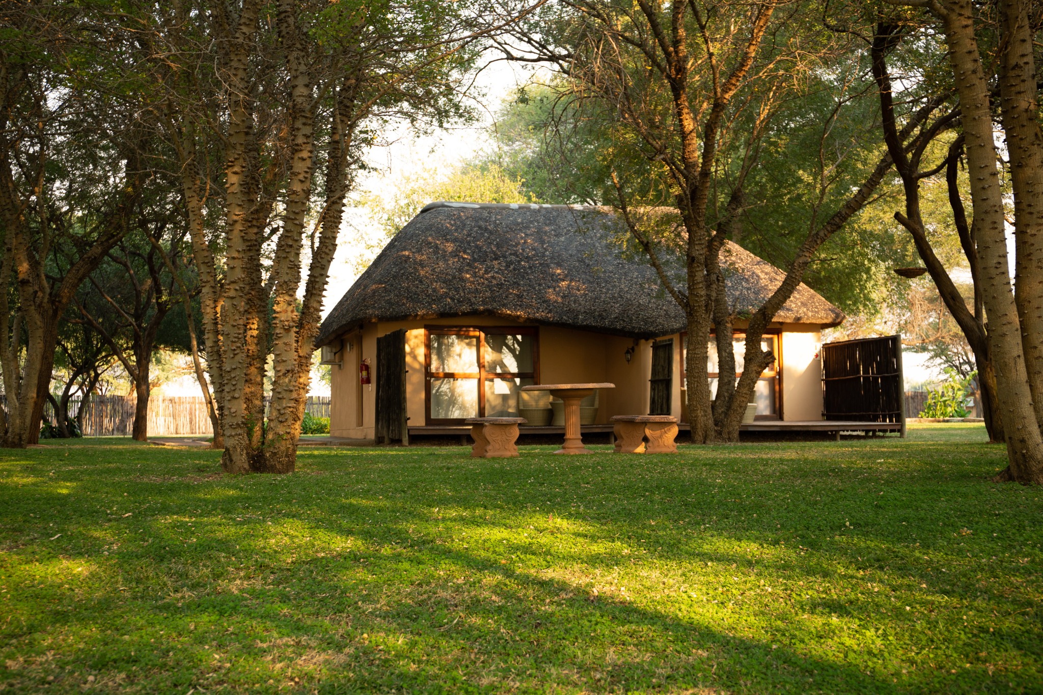 Thatched chalet surrounded by lawns and trees