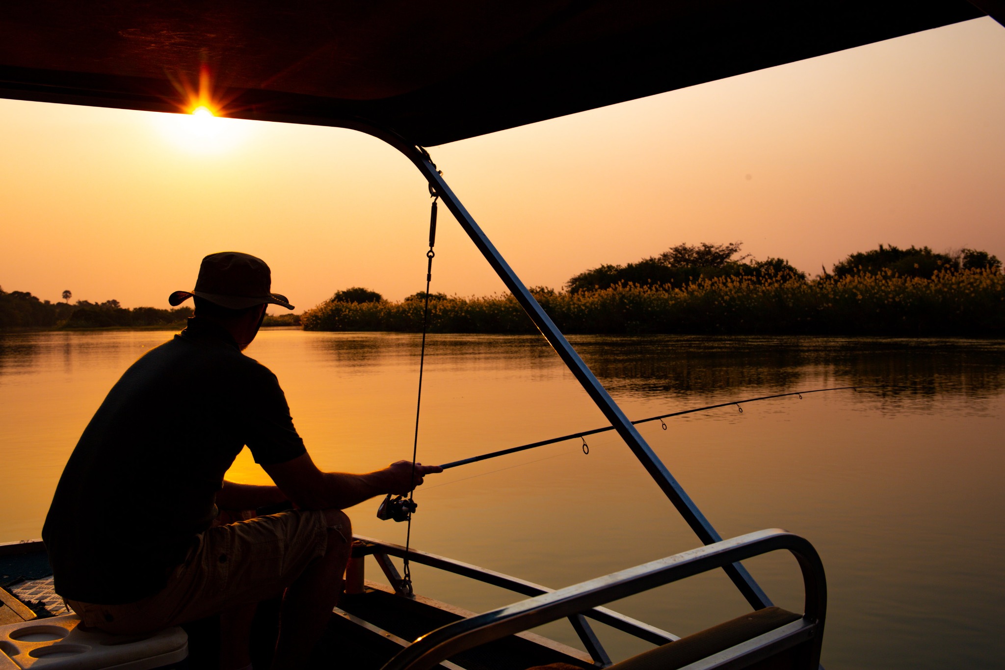 Angler fishing from a boat at sunset