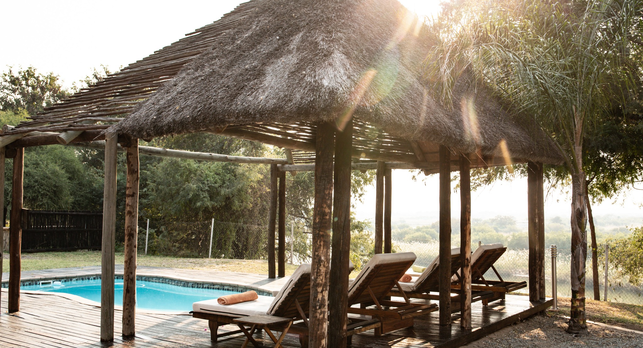 Sun loungers beside a pool and thatched deck